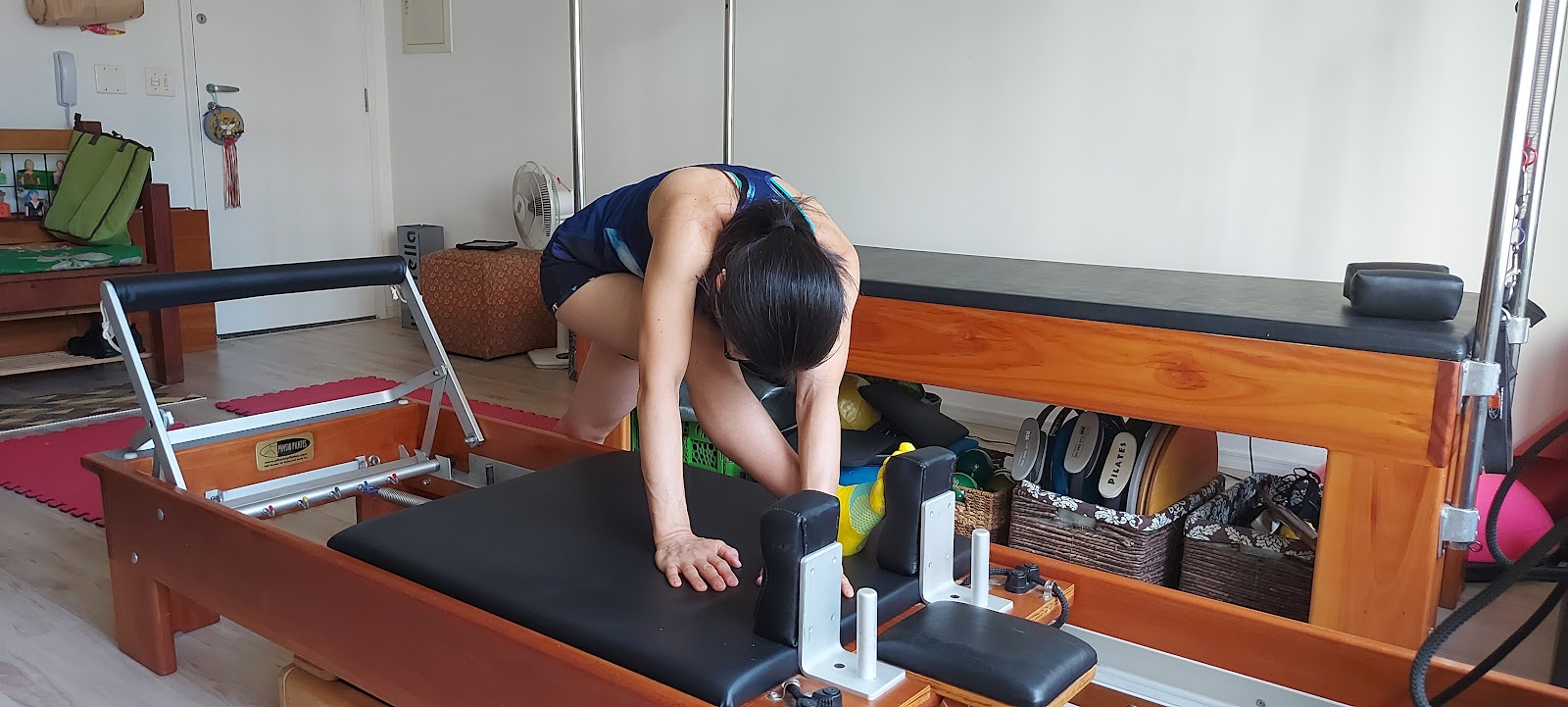 Professora ajustando o movimento de uma aluna no reformer